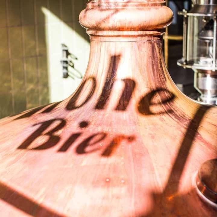 Kupfernes Braukessel mit dem Schatten der Worte „Bier“ und „ohe“ auf der Oberfläche.