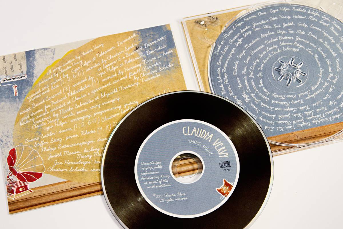 Geöffnete CD-Hülle mit Booklet und CD, beide mit handschriftlich wirkender weißer Schrift auf blauem Hintergrund gestaltet, dekoriert mit kleinen Illustrationen.