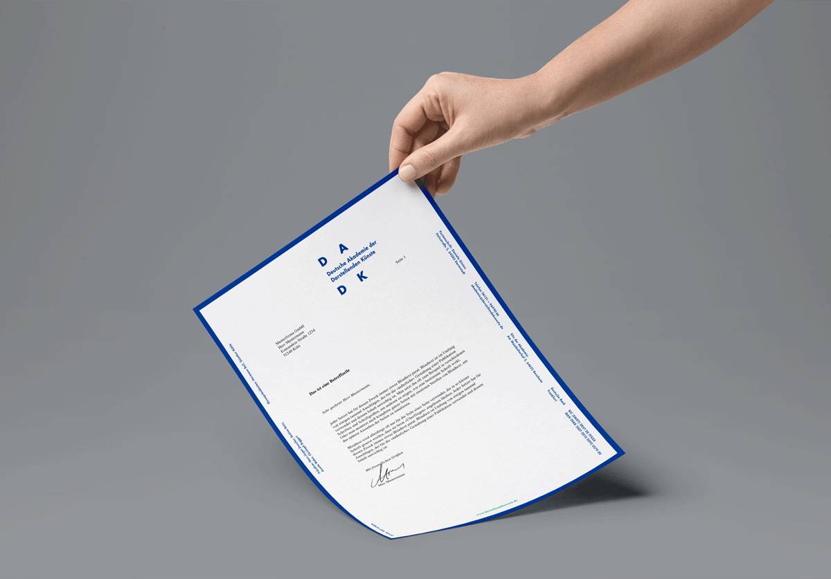 Eine Hand hält ein offizielles, weißes Dokument mit blauem Rand und blauer Schrift auf grauem Hintergrund.
