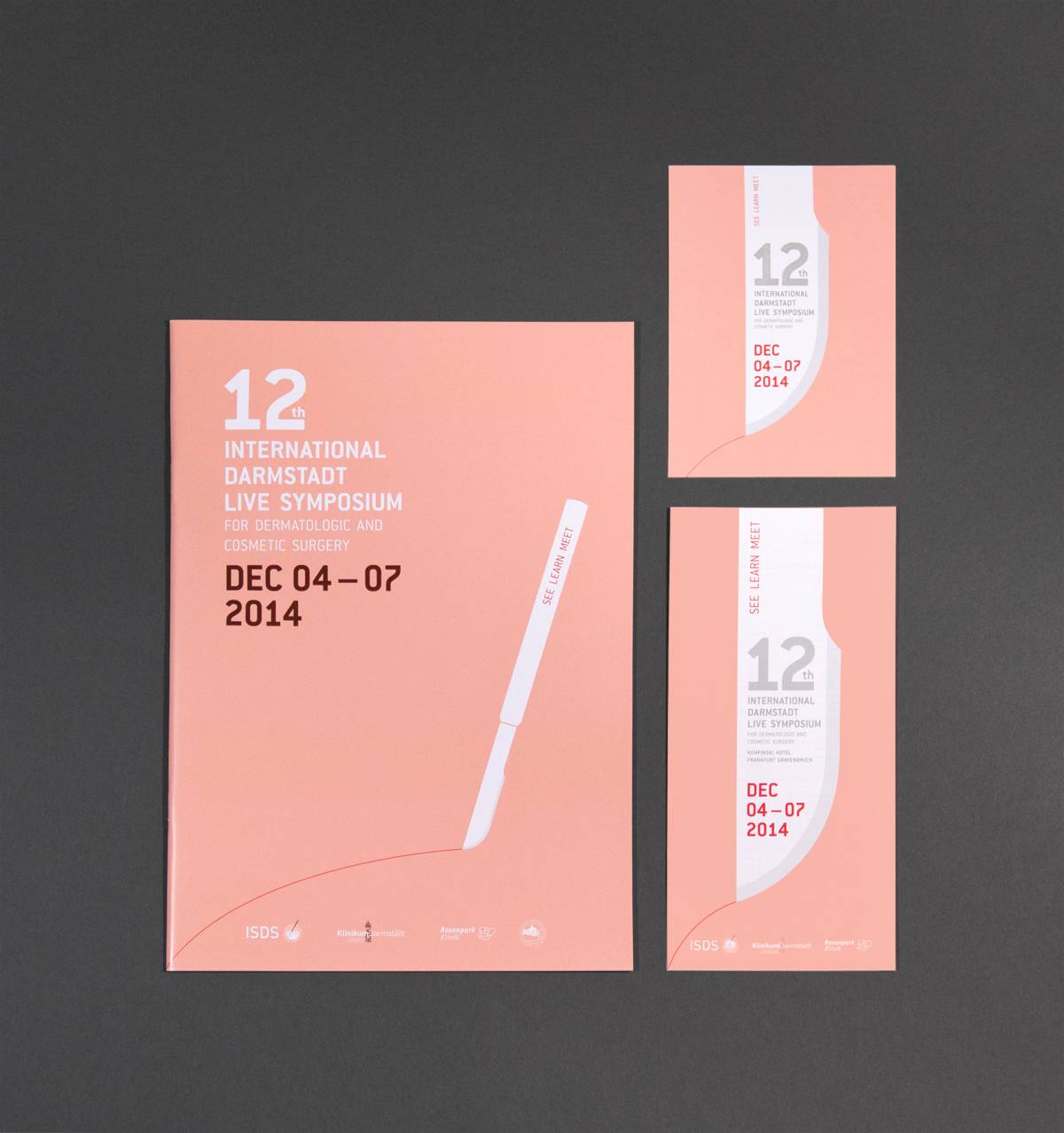 Drei rosafarbene Flyer und Broschüren für das 12. Internationale Darmstadt Live Symposium 2014, mit weißer und roter Schrift sowie einem stilisierten Skalpell.