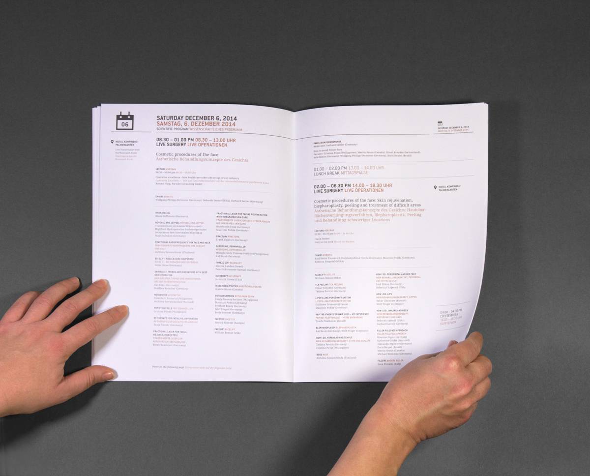Zwei Hände halten ein aufgeschlagenes Programmheft mit Text auf Deutsch und Englisch auf weißem Papier.