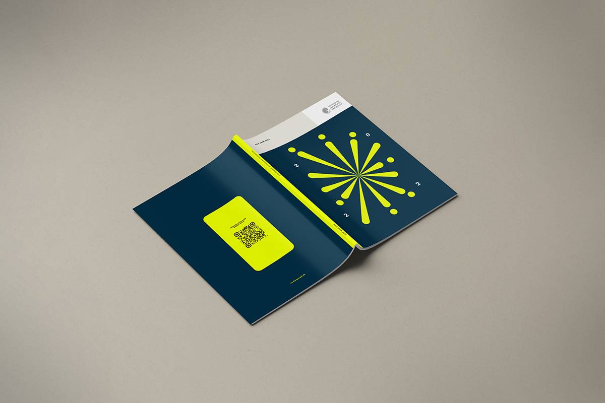 Aufgeklapptes, dunkelblaues Magazin mit gelbem grafischem Muster auf dem Cover und gelbem Rechteck mit QR-Code auf der Innenseite, auf hellem Hintergrund.