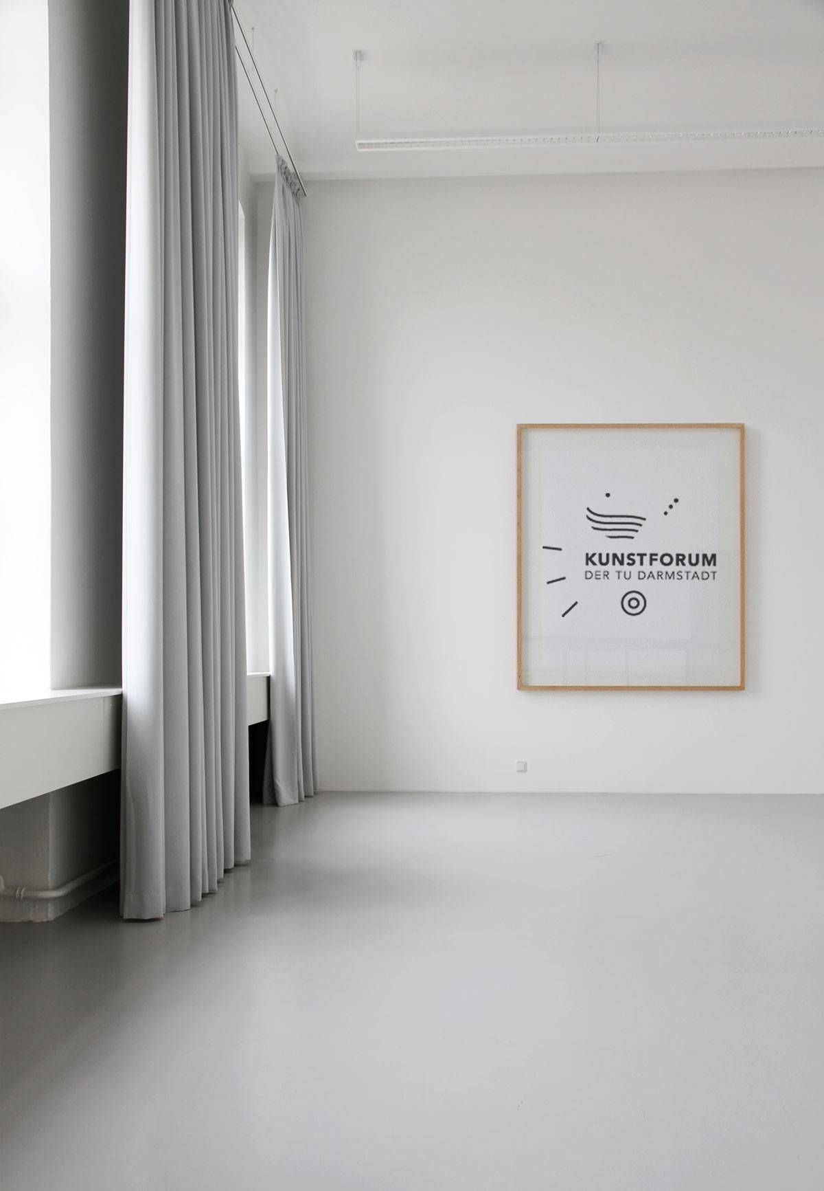 Heller, leerer Raum mit großen Fenstern, grauen Vorhängen und einem gerahmten Plakat an der weißen Wand mit der Aufschrift "Kunstforum der TU Darmstadt".