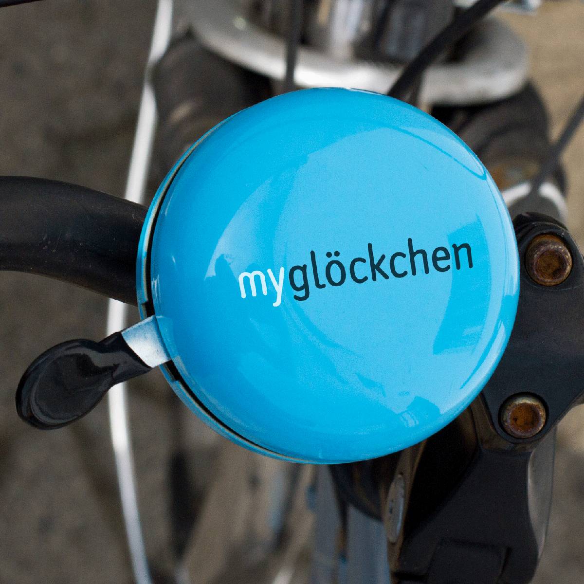 Blaue Fahrradklingel mit der Aufschrift „myglöckchen“ am Lenker montiert.
