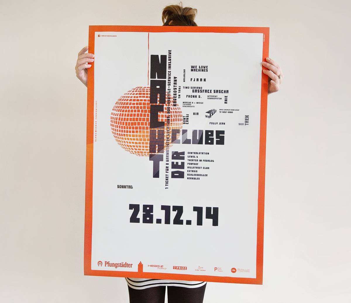 Person hält ein großes Plakat mit dem Titel „Nacht der Clubs“, einem grafischen orangefarbenen Kreis und dem Datum 28.12.14.