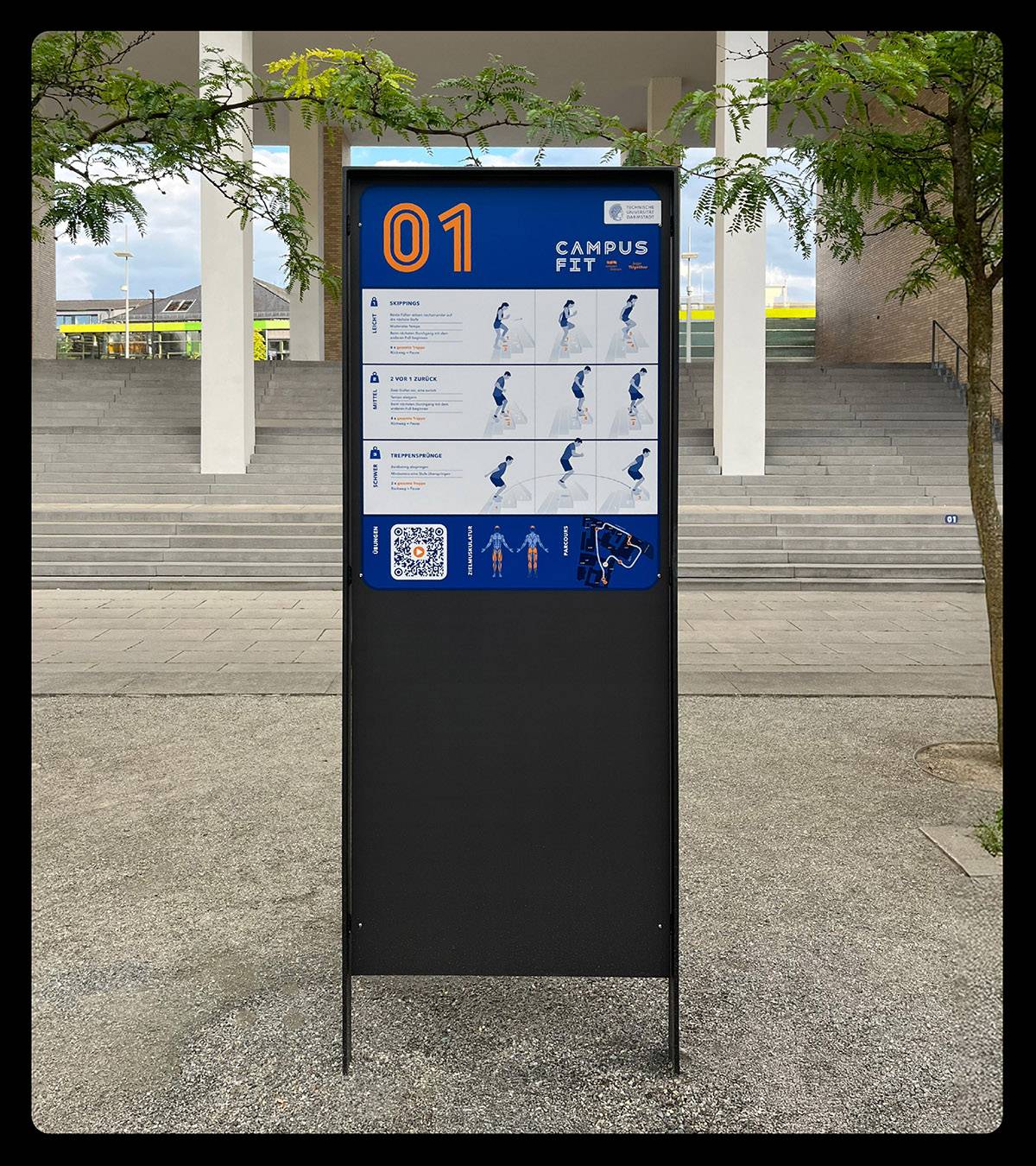 Outdoor-Infotafel mit der Überschrift „Campus Fit“ und der Nummer 01, zeigt Anleitungen und Illustrationen für Fitnessübungen, steht vor einer Treppe im Freien.