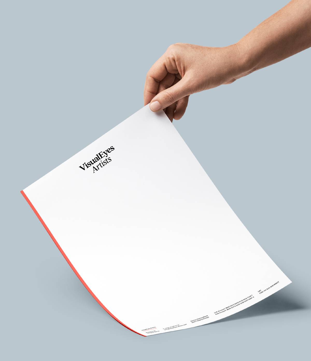 Eine Hand hält ein weißes Blatt Papier mit rotem Rand, auf dem oben links „VisualEyes Artists“ steht.
