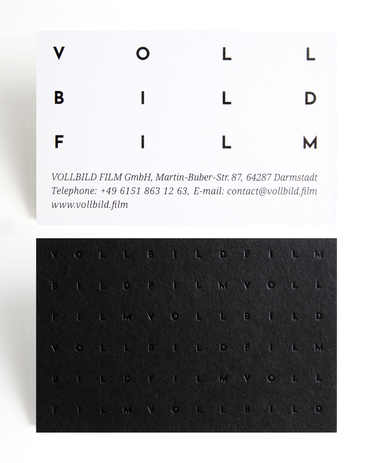 Zwei Visitenkarten: Oben eine weiße Karte mit großem, weit auseinander geschriebenem "VOLLBILD FILM" und Kontaktdaten der Firma, unten eine schwarze Karte mit geprägtem, kleingeschriebenem "VOLLBILD FILM" in Musterform.